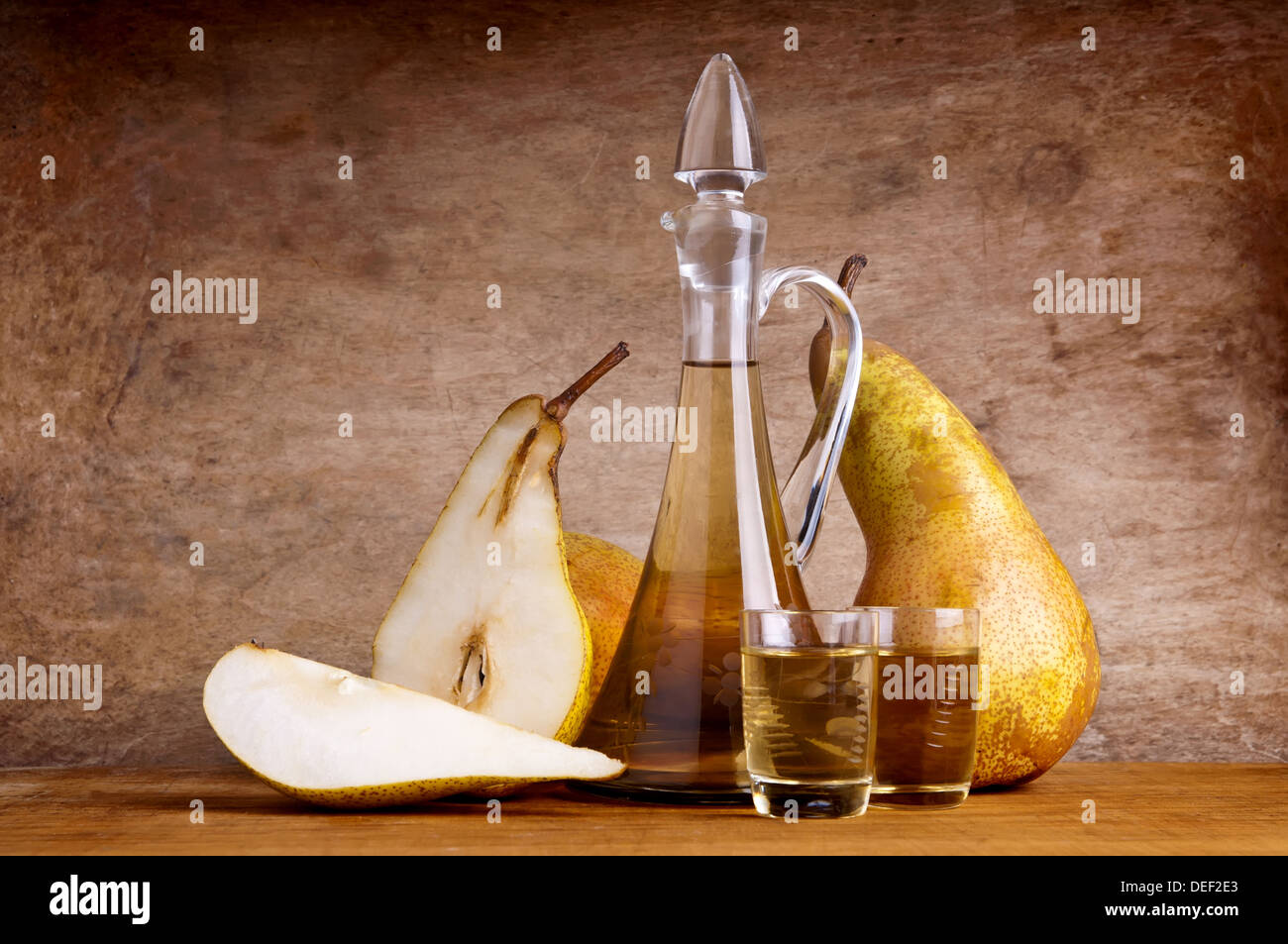 Stillleben-Komposition mit Obstbrand und Birnen auf einem hölzernen Vintage-Hintergrund Stockfoto