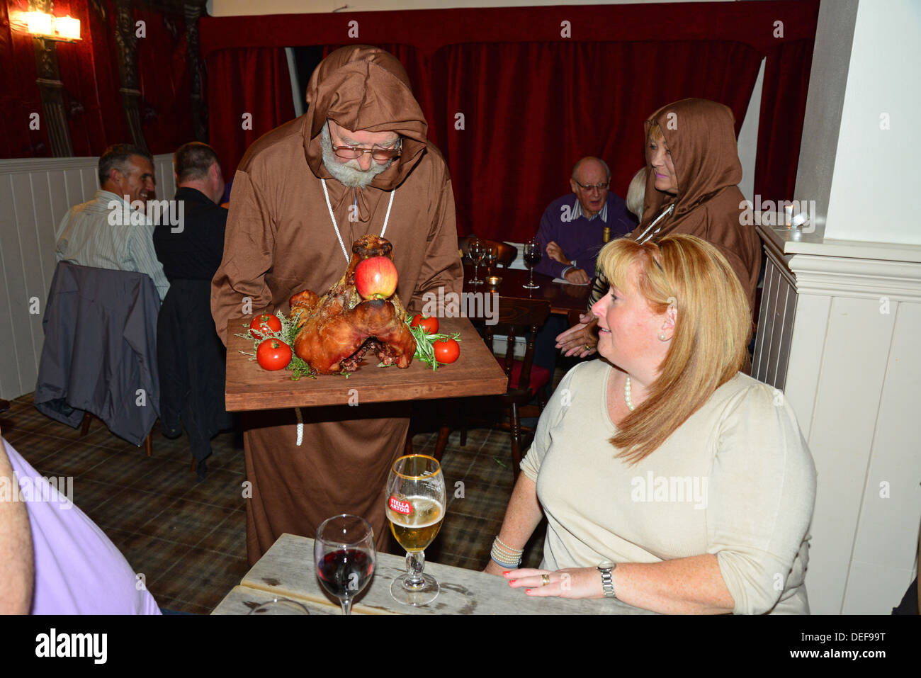 Mönch mit Spanferkel Schweinekopf nachts mittelalterliches Festmahl The Wheatsheaf Pub, Crick, Northamptonshire, England, Vereinigtes Königreich Stockfoto