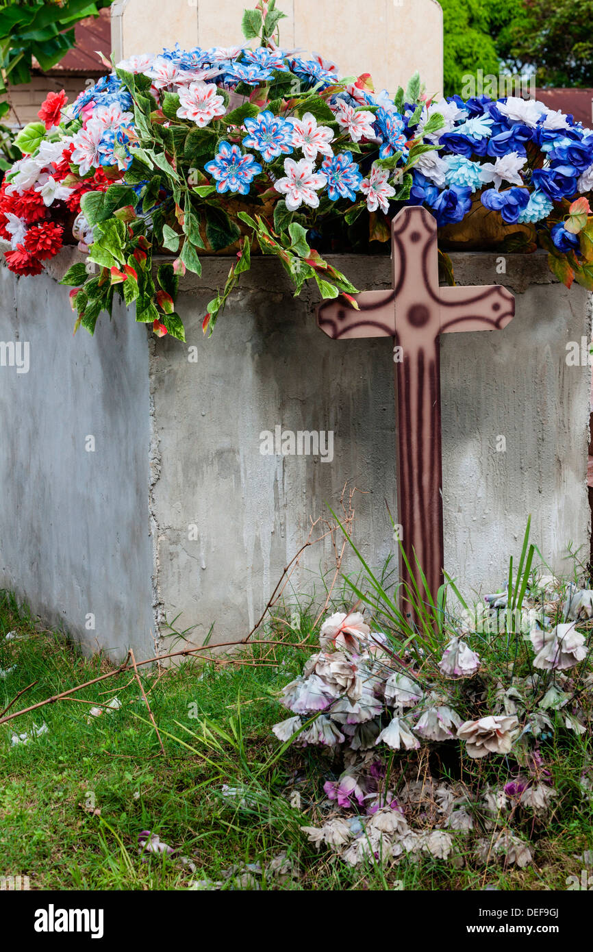 Afrika, Gabun, Libreville. Kunstblumen oben Kreuz im Friedhof. Stockfoto