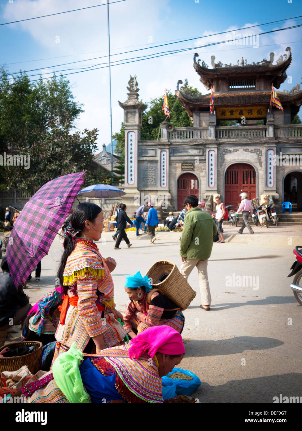 Flower Hmong Leute am Sonntagsmarkt in Bac Ha, Vietnam.  Die Bac Ha Tempel erhebt sich im Hintergrund. Stockfoto