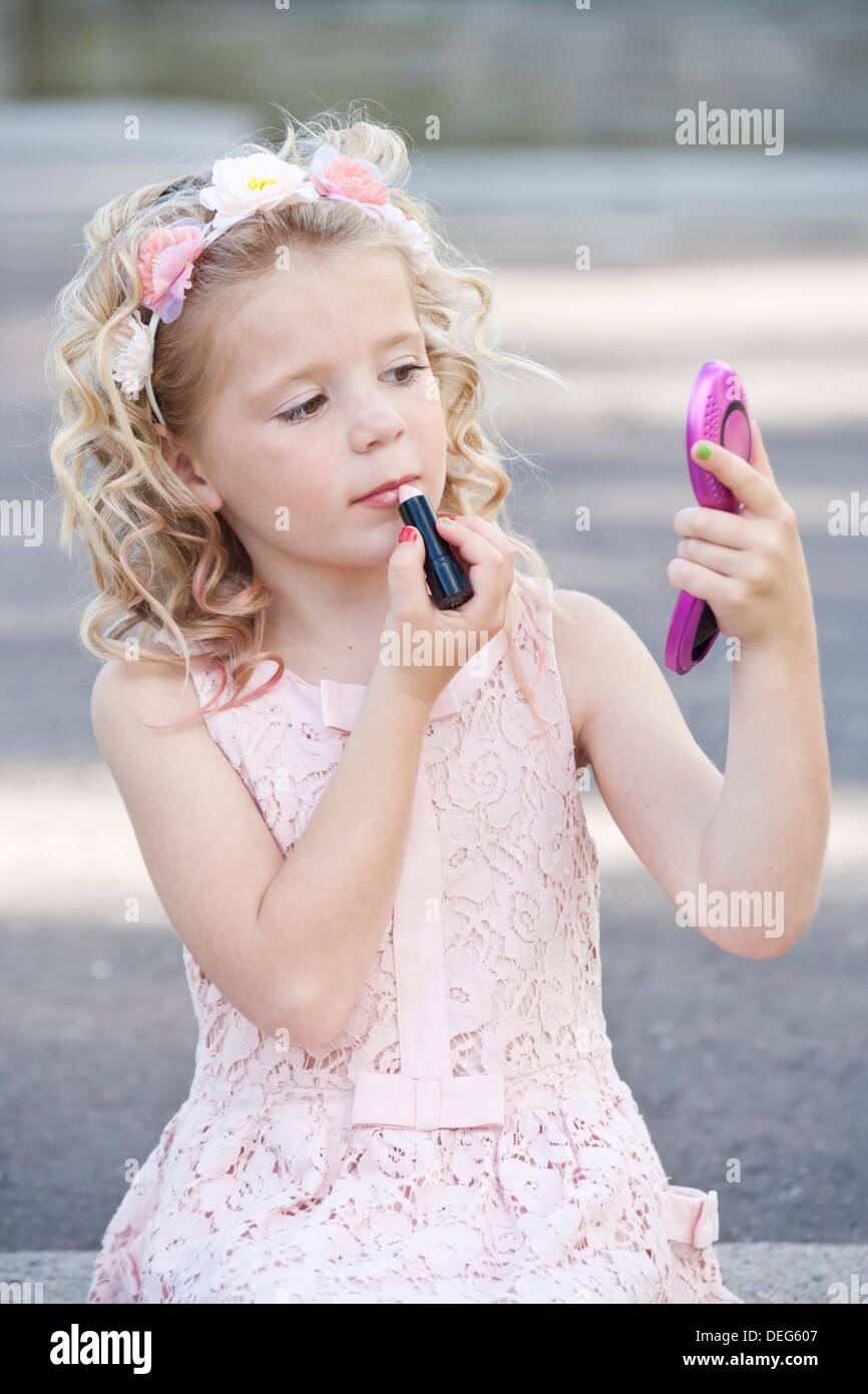 Ziemlich sieben Jahre altes Mädchen tragen rosa und Auftragen von Lippenstift Stockfoto