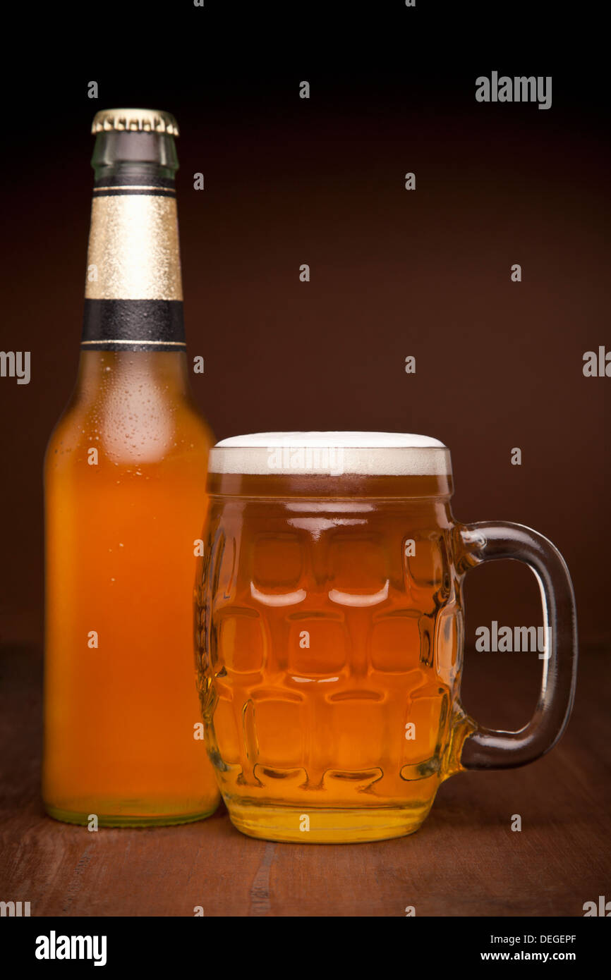 Ein Glas und eine Flasche Bier auf einem Holztisch. Stockfoto