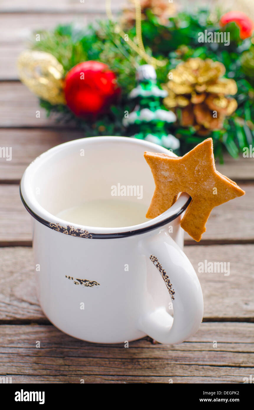 Becher mit Milch und Kekse in Form von Sternen auf dem Hintergrund der Weihnachtskranz abgeschlagen Stockfoto