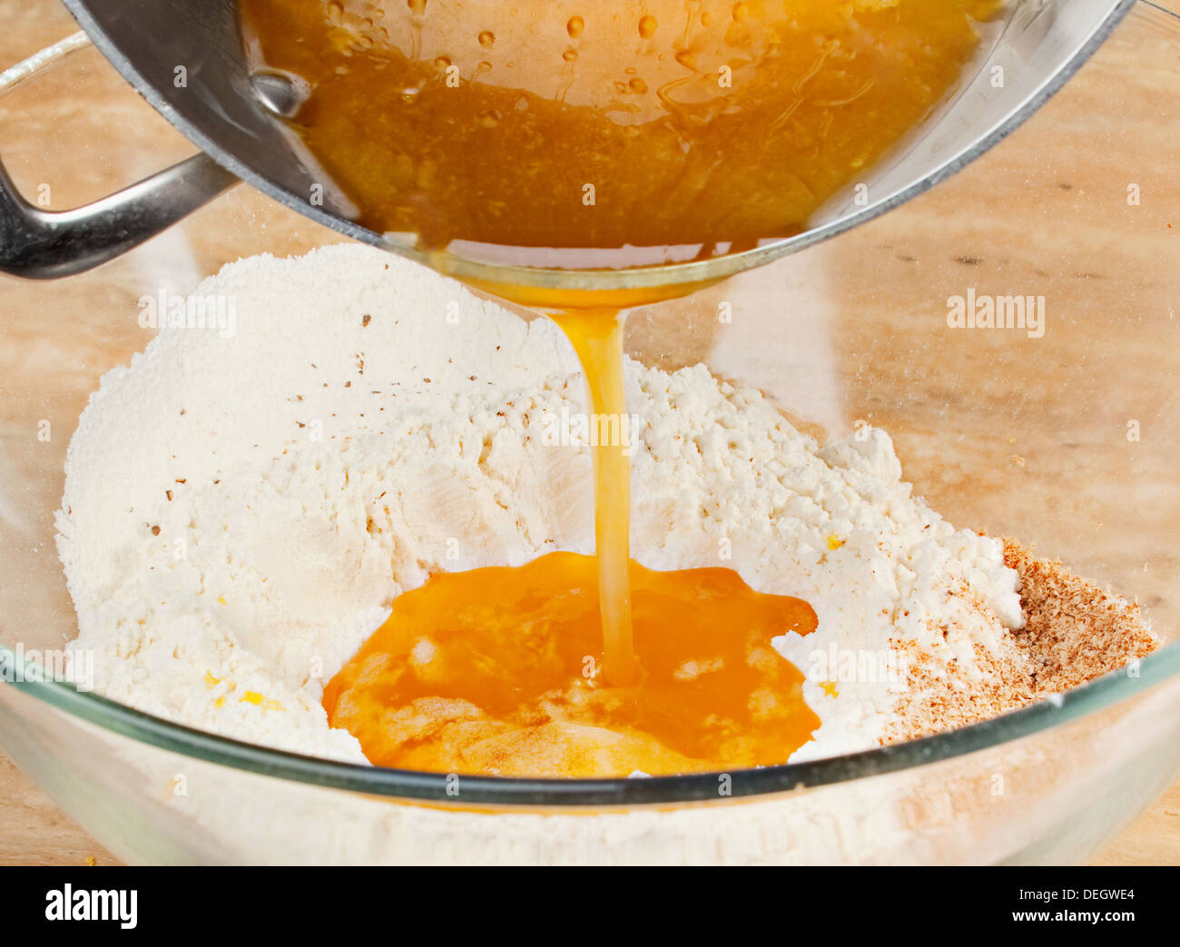 Geschmolzenen Honig und Butter im Mehl hinzufügen Stockfoto