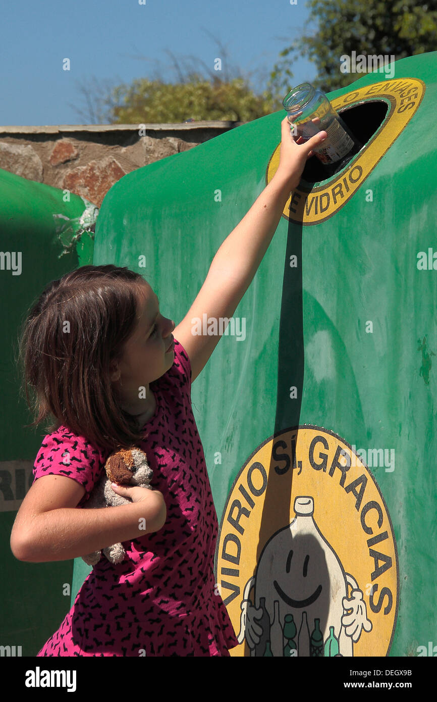 Ein junges Mädchen (7-8 Jahre), ein Glas recycling Stockfoto