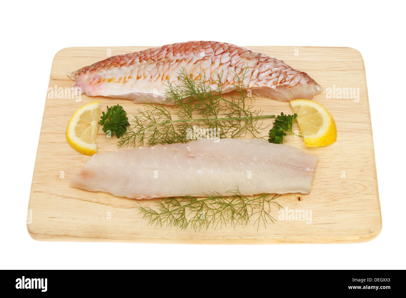 Rohe Filets von Rotbarbe Fisch auf einem Holzbrett mit Zitrone, Petersilie und Fenchel isoliert gegen weiß Stockfoto