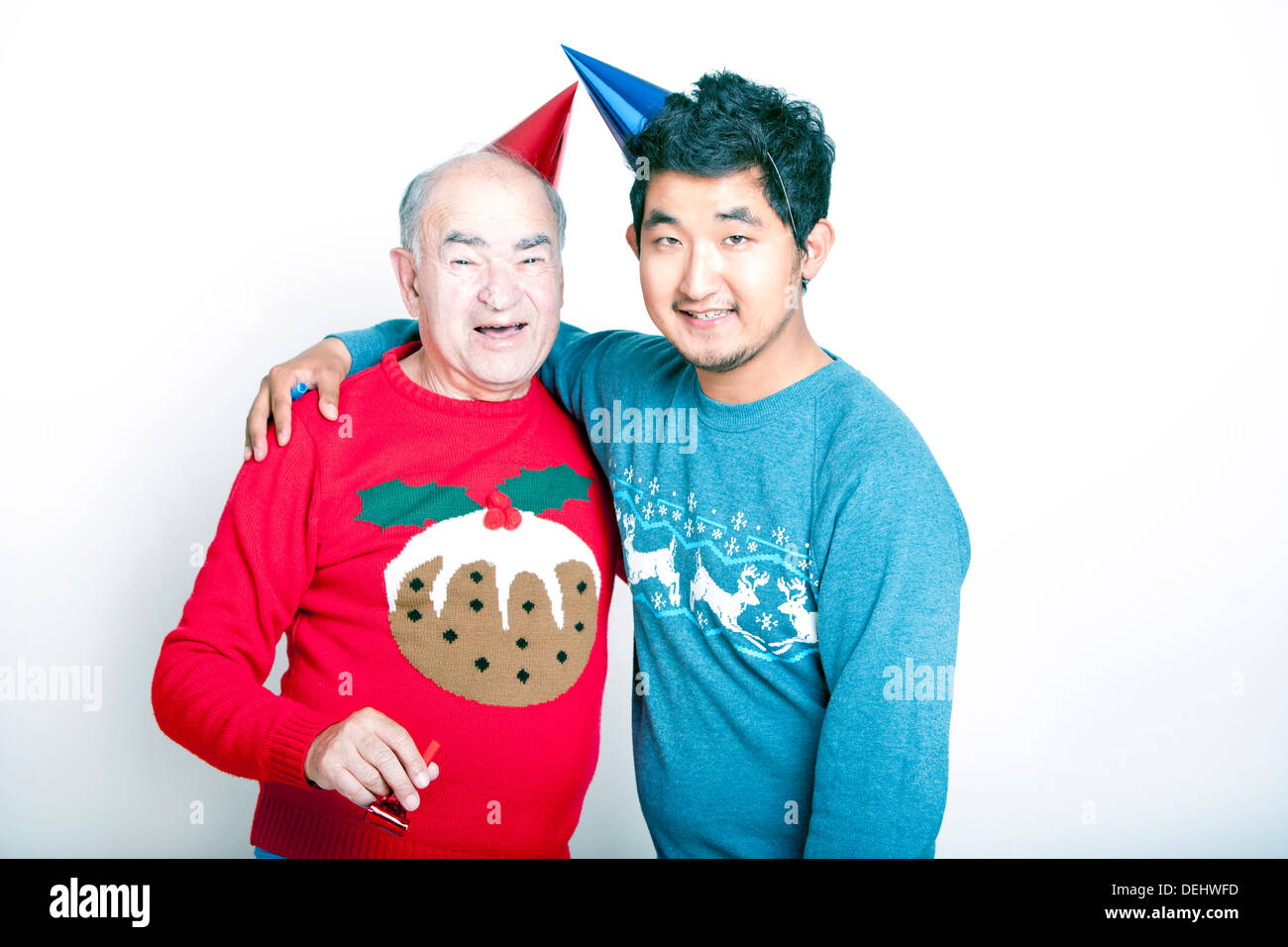 Porträt eines älteren Erwachsenen Mann ein jungen asiatischen Mann tragen Weihnachten Jumper Partyhüte Stockfoto