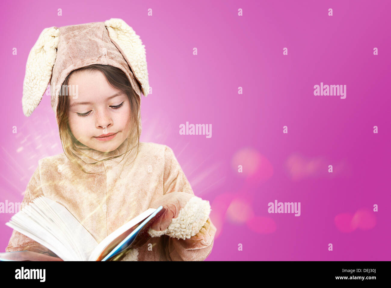 Kleines Mädchen, gekleidet wie ein Hase, ein Buch zu lesen Stockfoto
