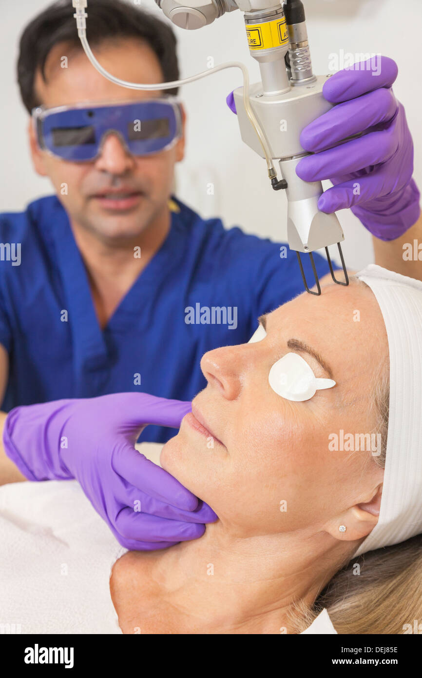 Ein Schönheitschirurg Arzt geben fraktionierte CO2-Laser Hautbehandlung auf das Gesicht eines älteren weiblichen Frau Patienten Stockfoto