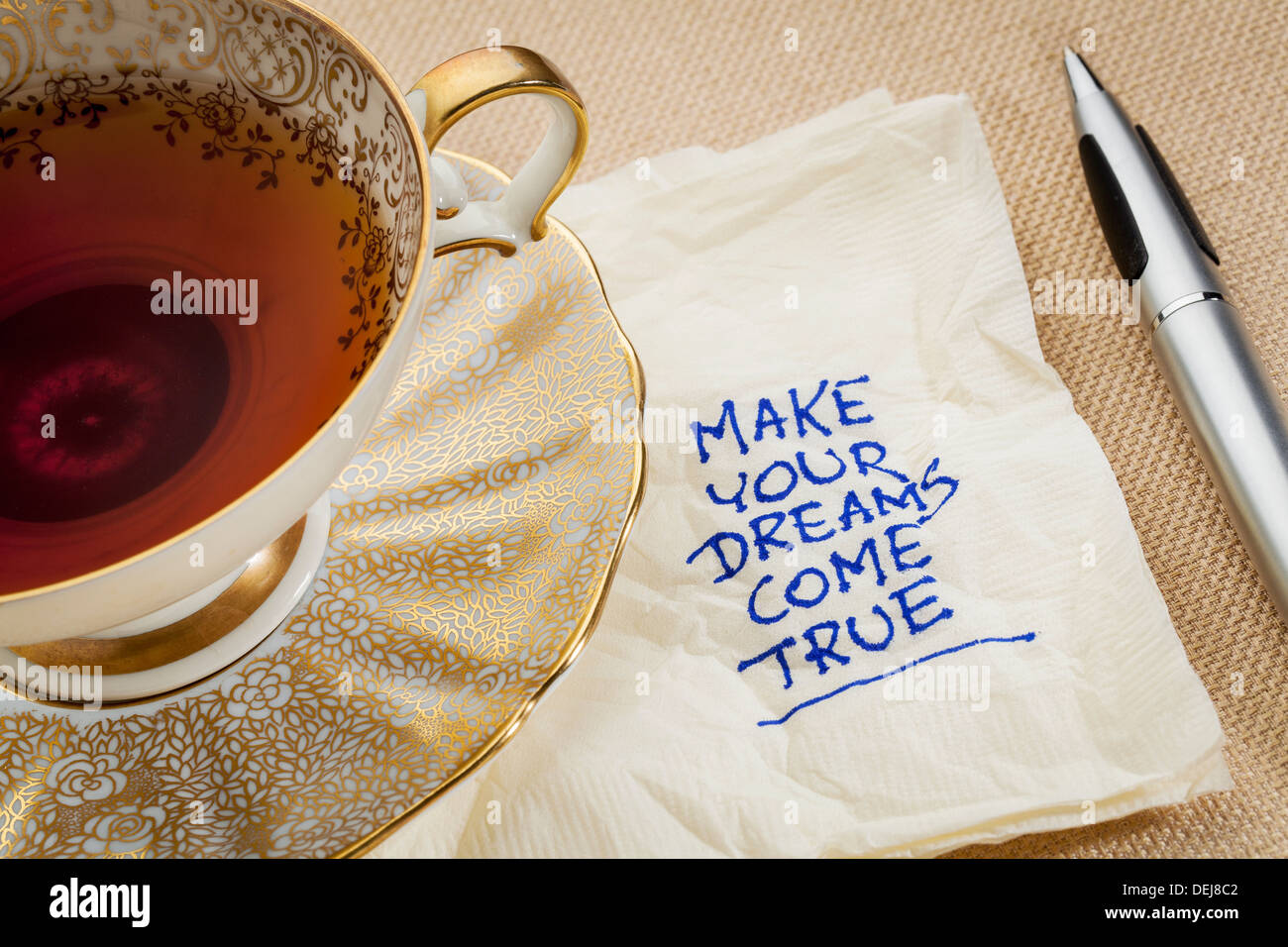 machen Sie Ihre Träume wahr - Motivations Slogan auf einer Serviette mit Tasse Tee Stockfoto