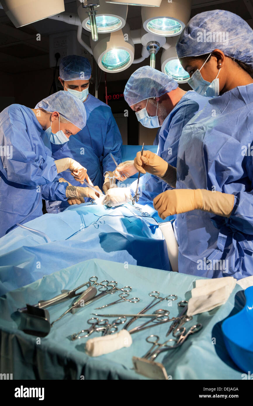 Interracial Ärzte Chirurgen-Team in der Chirurgie auf einem Patienten im Theater tragen scheuert Masken Handschuhe Stockfoto