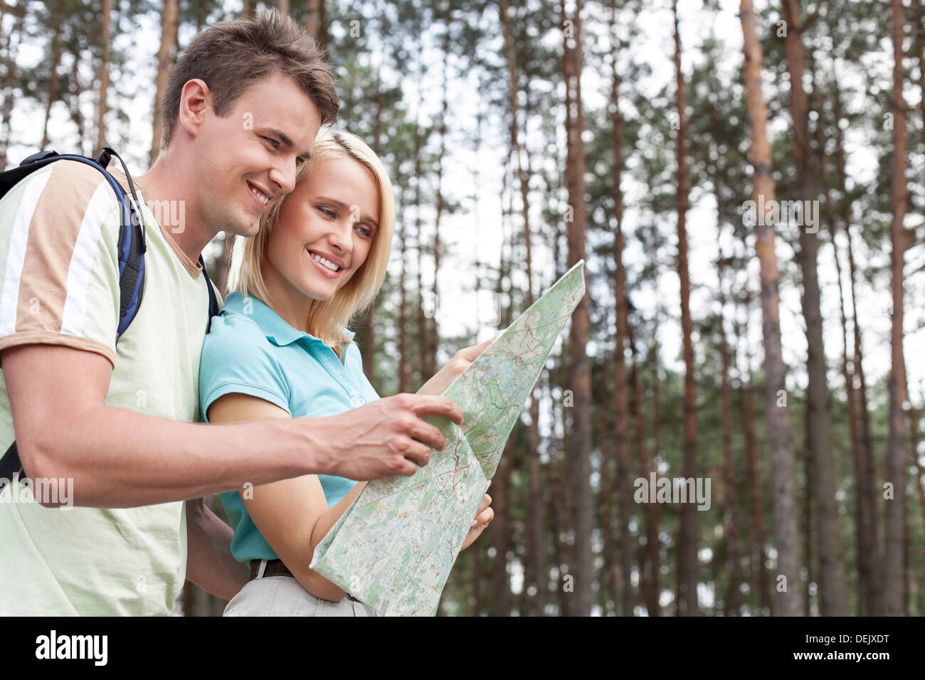 Glückliche junge Rucksacktouristen, die auf der Suche Karte Wald Stockfoto