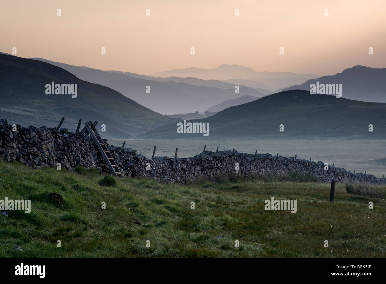 Blick entlang der Landschaft Felder in Richtung nebligen Snowdonia Bergkette in Ferne Stockfoto