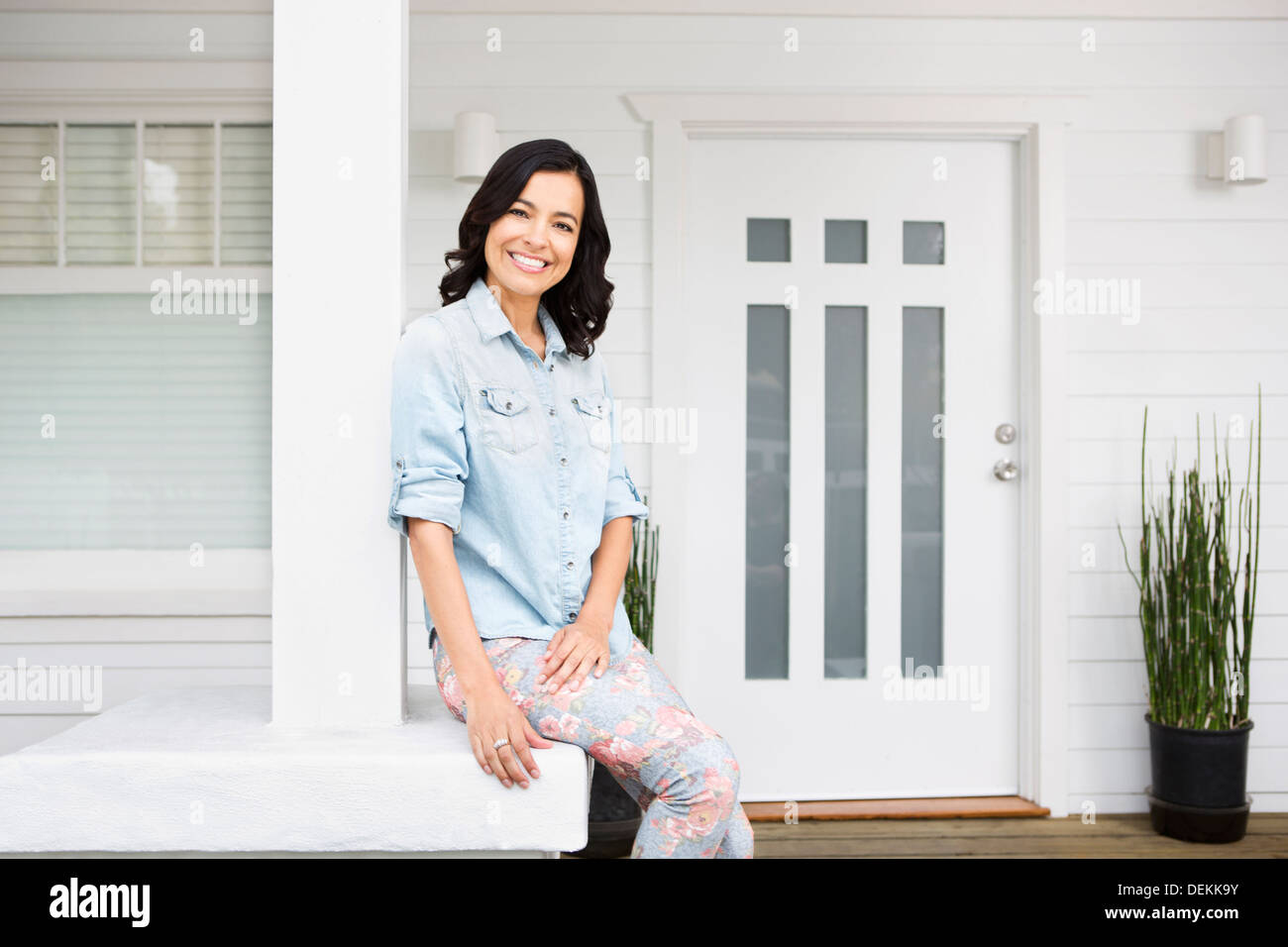 Hispanic Frau lächelnd auf Veranda Stockfoto