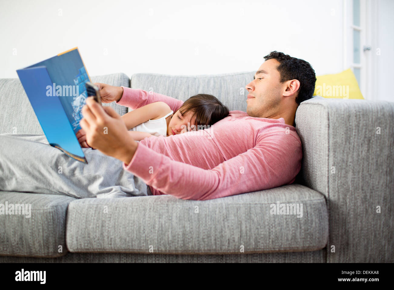 Vater und Tochter gemeinsam auf Sofa lesen Stockfoto