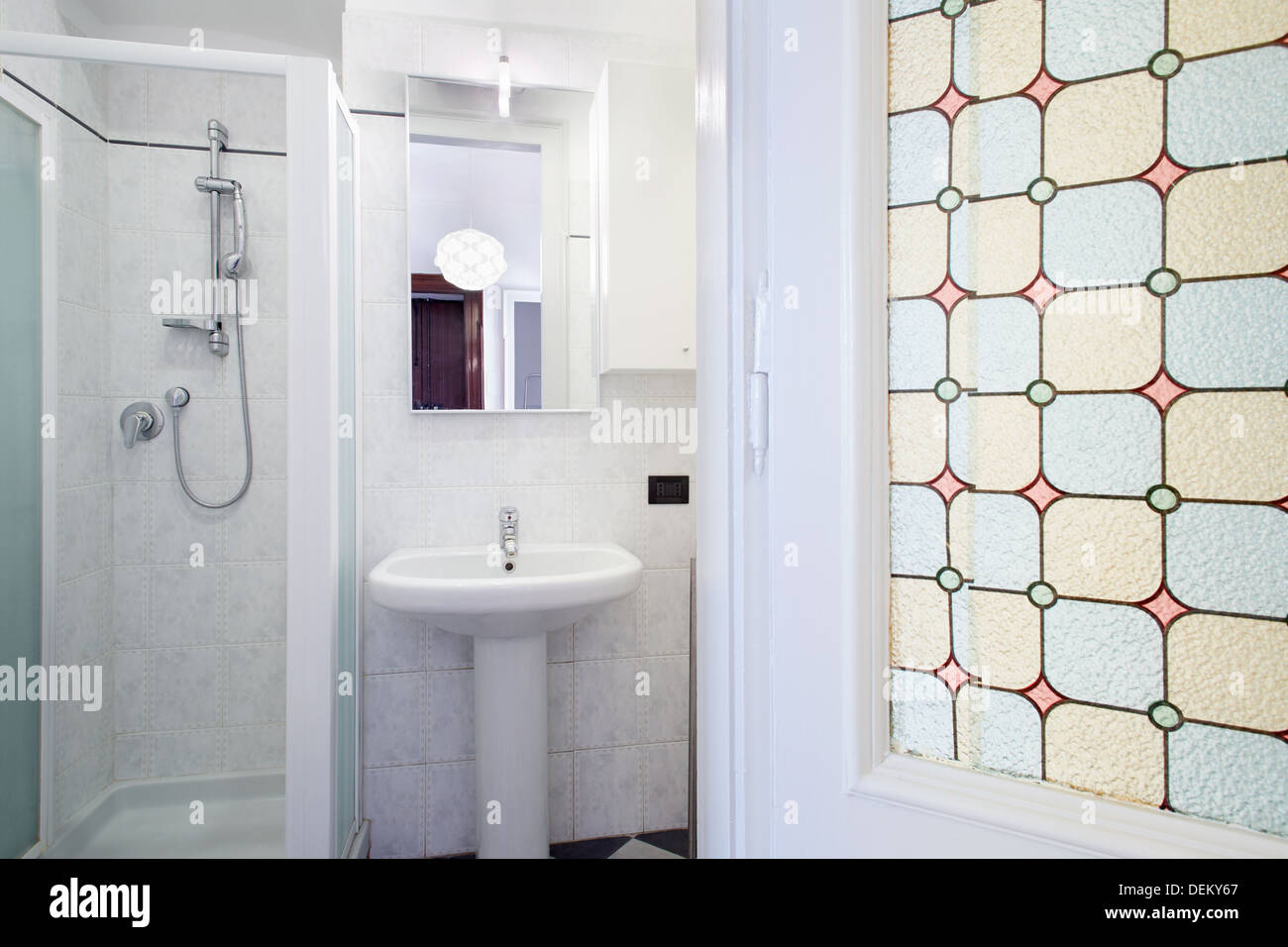 Ein kleines Bad mit weißen Fliesen und grünen Zierleisten an den Wänden, es  gibt einen Spiegel über dem Waschbecken Stockfotografie - Alamy