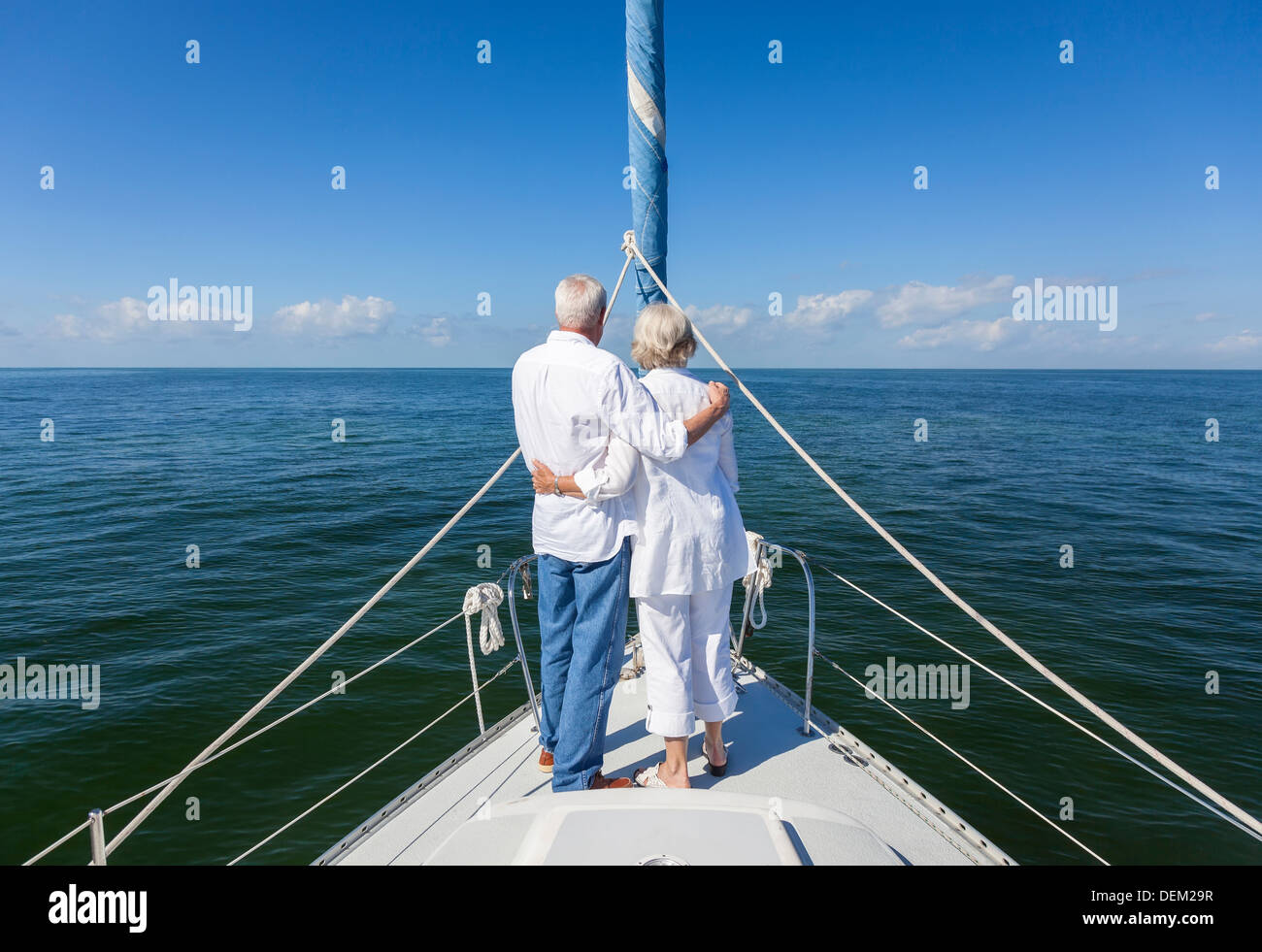 Ein glückliches senior paar vorn oder Bogen eines Segelbootes auf einem ruhigen blauen Meer Blick auf einen klaren Horizont umarmen Stockfoto