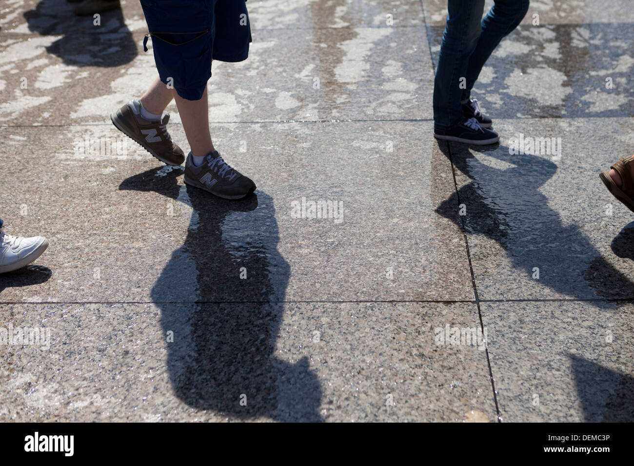 Nahaufnahme von Menschen zu Fuß auf nasser Fahrbahn Stockfoto