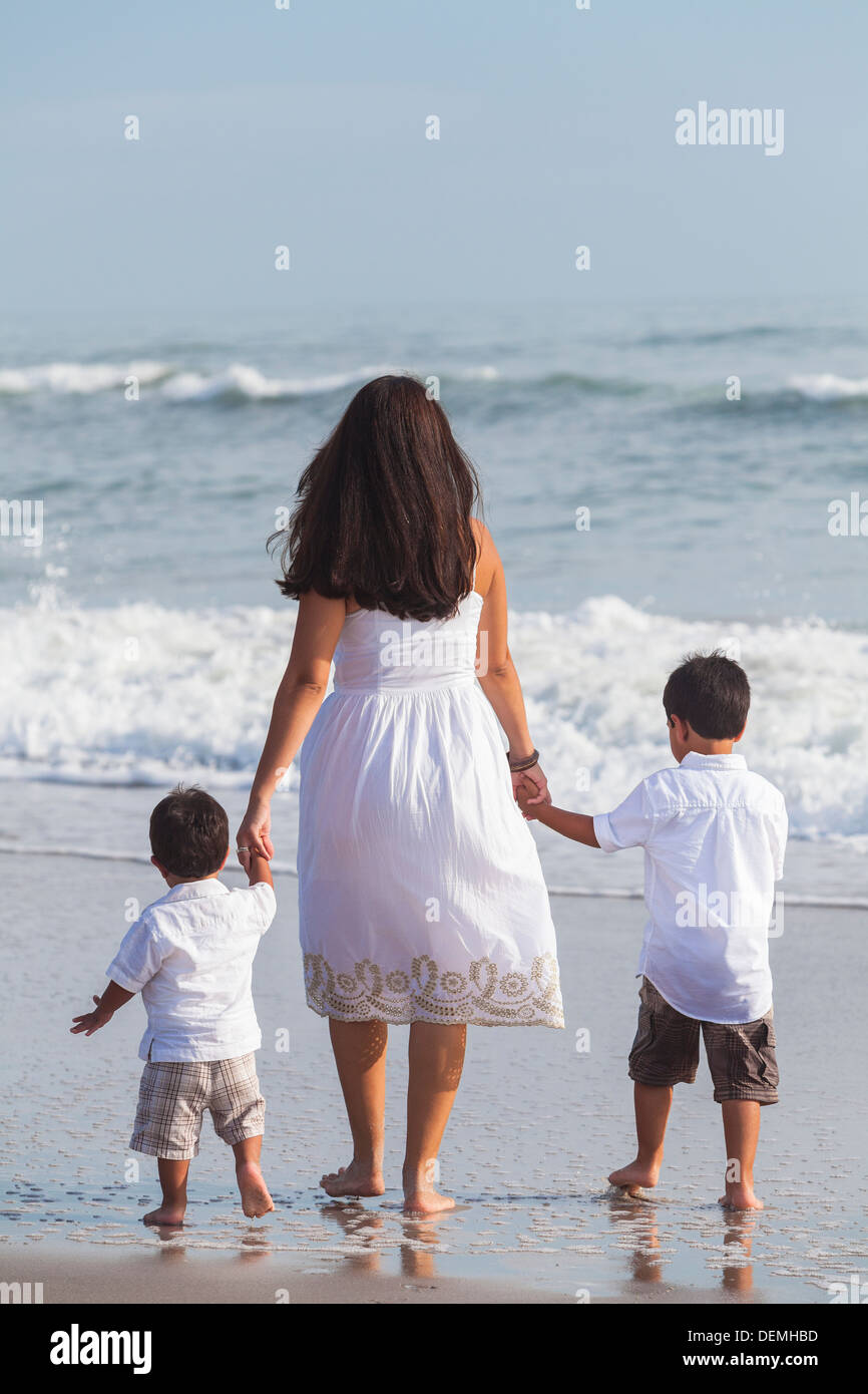 Familie der Mutter Eltern & zwei jungen Sohn Kinder, Hände Wandern und halten in den Wellen des Strandes Stockfoto