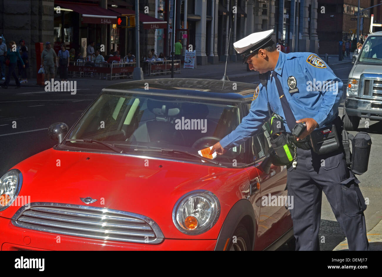 Ein Verkehrspolizist von New York City bietet ein Ticket zu einem geparkten Fahrzeug für eine abgelaufene Meter am Broadway in New York City Stockfoto