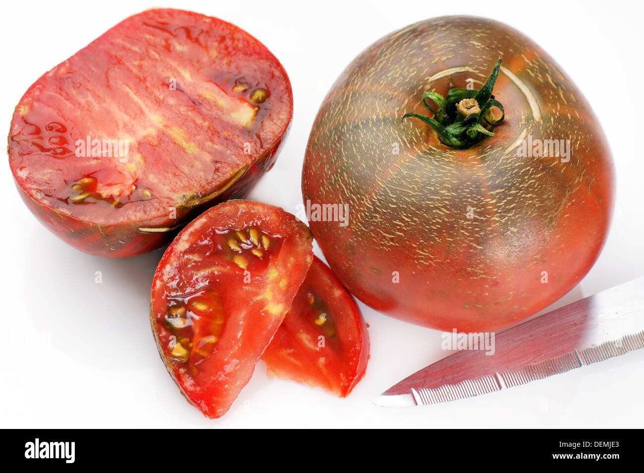 Heirloom Tomaten, ganz schwarz und in Scheiben schneiden mit Messer auf weiß Stockfoto