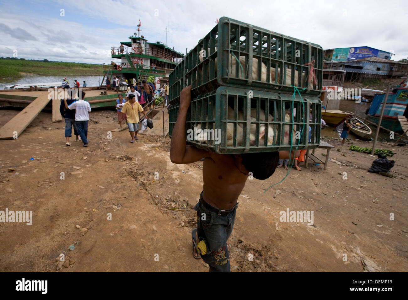 Ein Portier trägt aus dem Schiff mehrere Kisten Hühner zum Markt der Stadt voller. Stockfoto