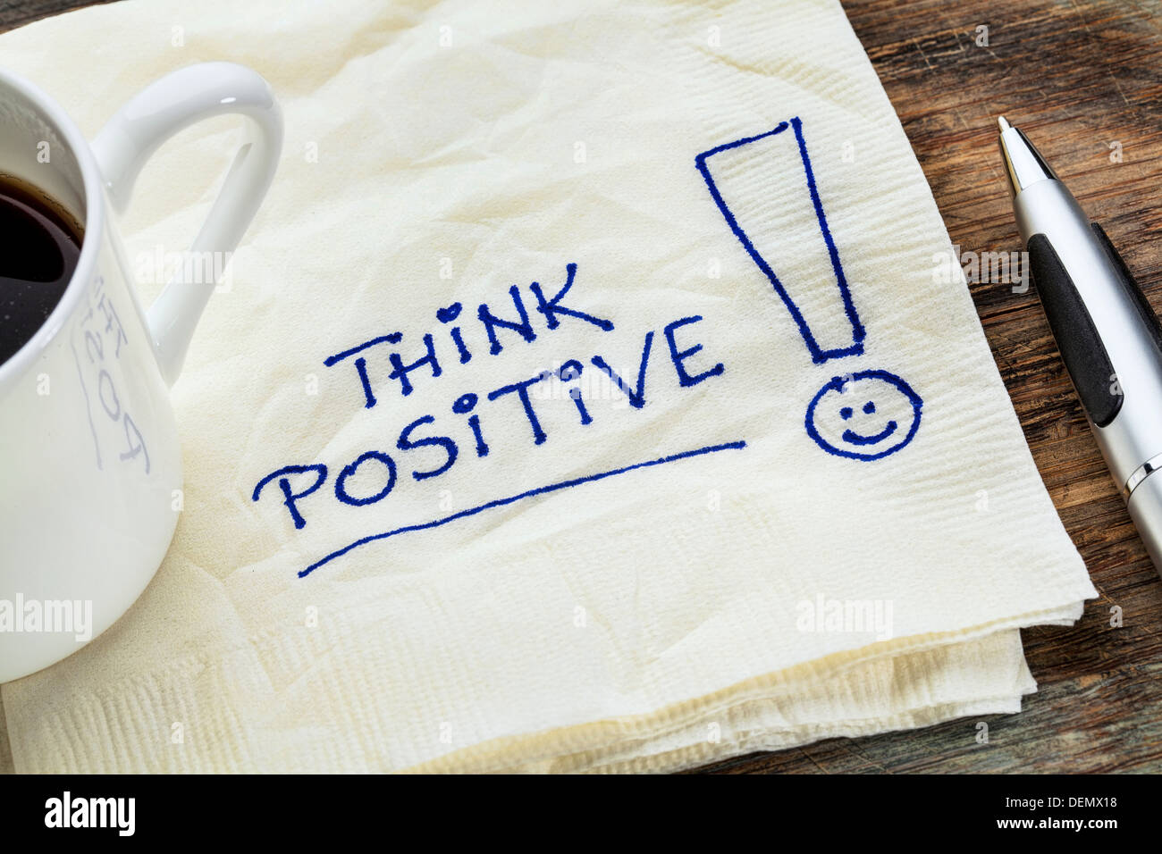 denke positiv - Motivations Slogan auf eine Serviette mit einer Tasse Kaffee Stockfoto