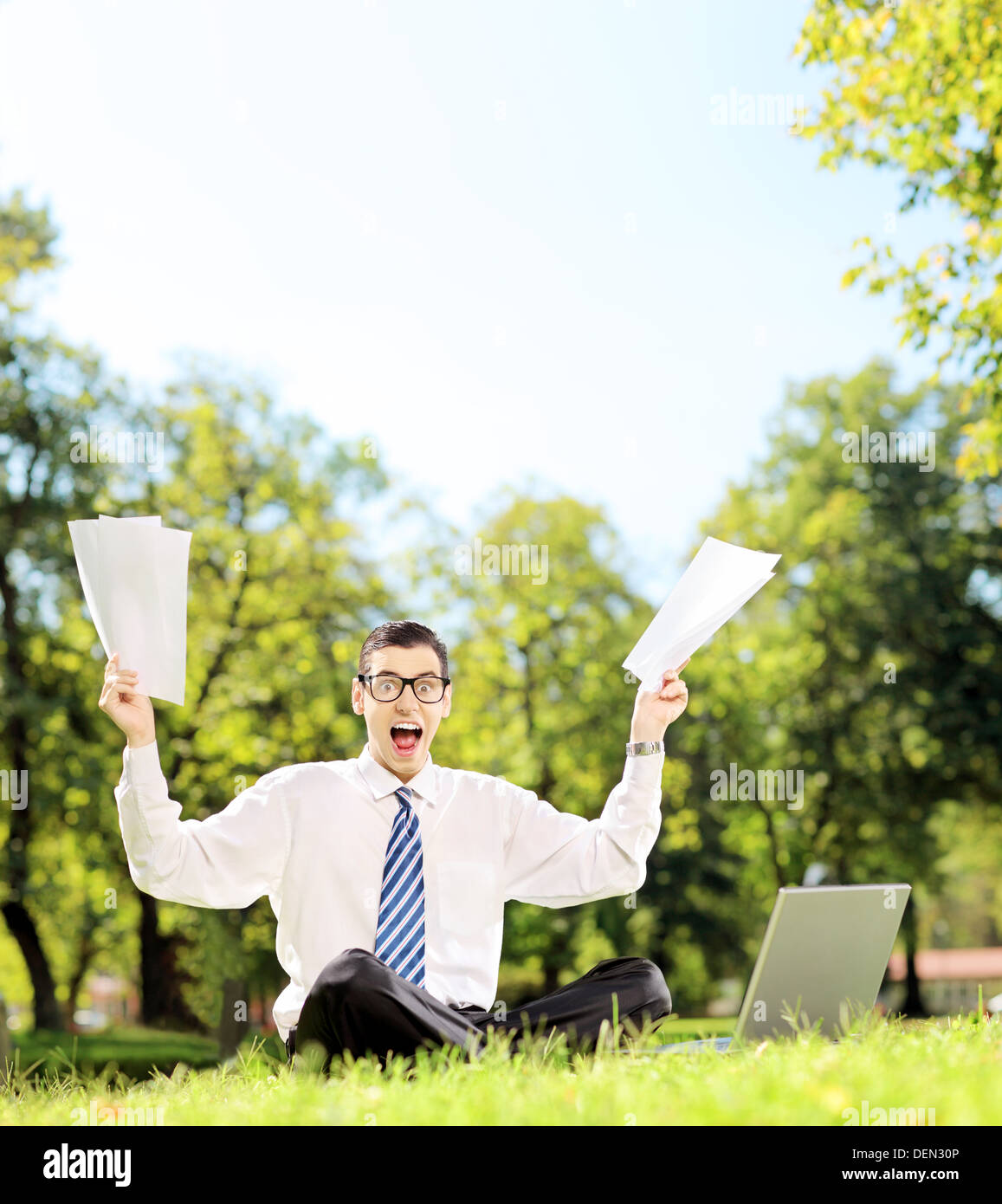 Besorgt junger Geschäftsmann Dokumente und schreien sitzen auf einer Wiese in einem park Stockfoto