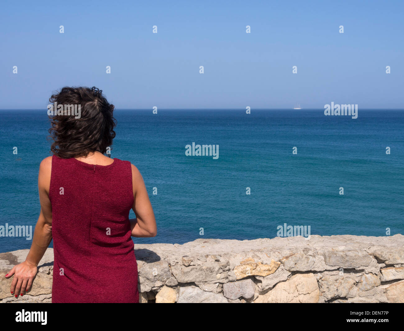 Frau mit rotem Kleid direkt am Meer Stockfoto