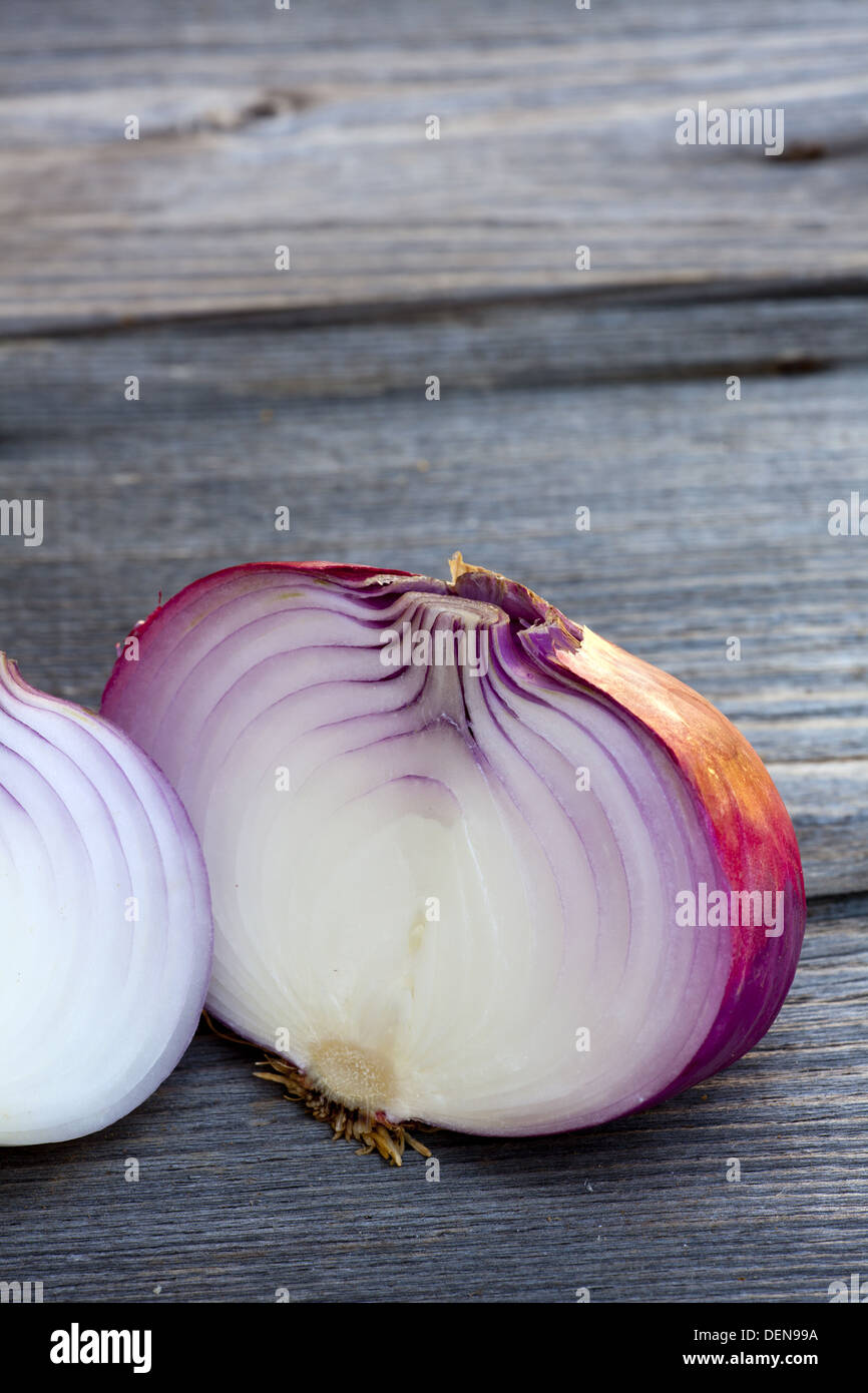 Nahaufnahme des ganzes und eine halbierte frische rote Zwiebel auf einem alten Holztisch Stockfoto