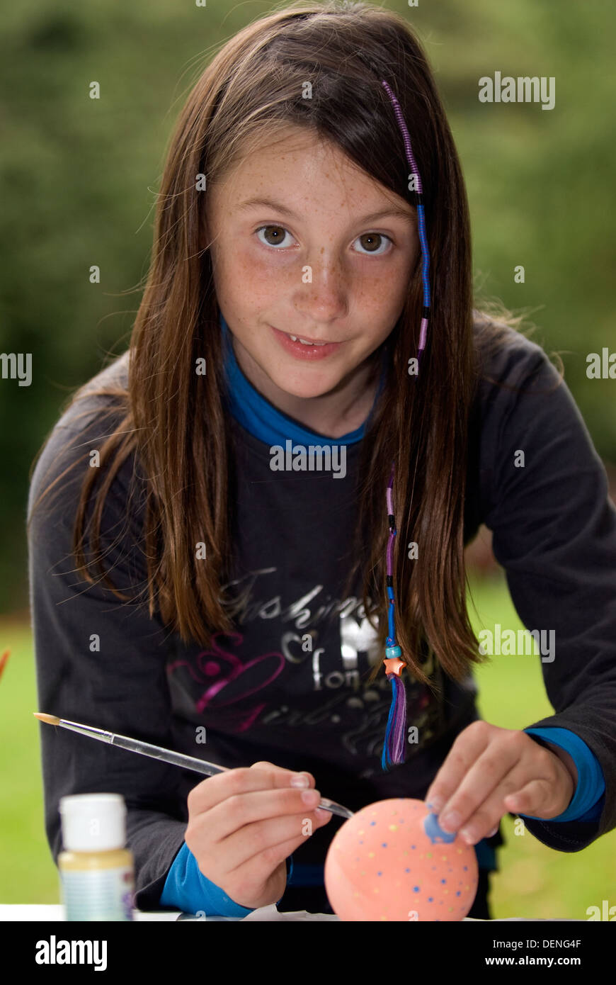 9-Jähriges Mädchen Verzieren einer Weihnachtskugel zu einem Außenpool im Sommer zeigen, liphook, Hampshire, UK. Stockfoto