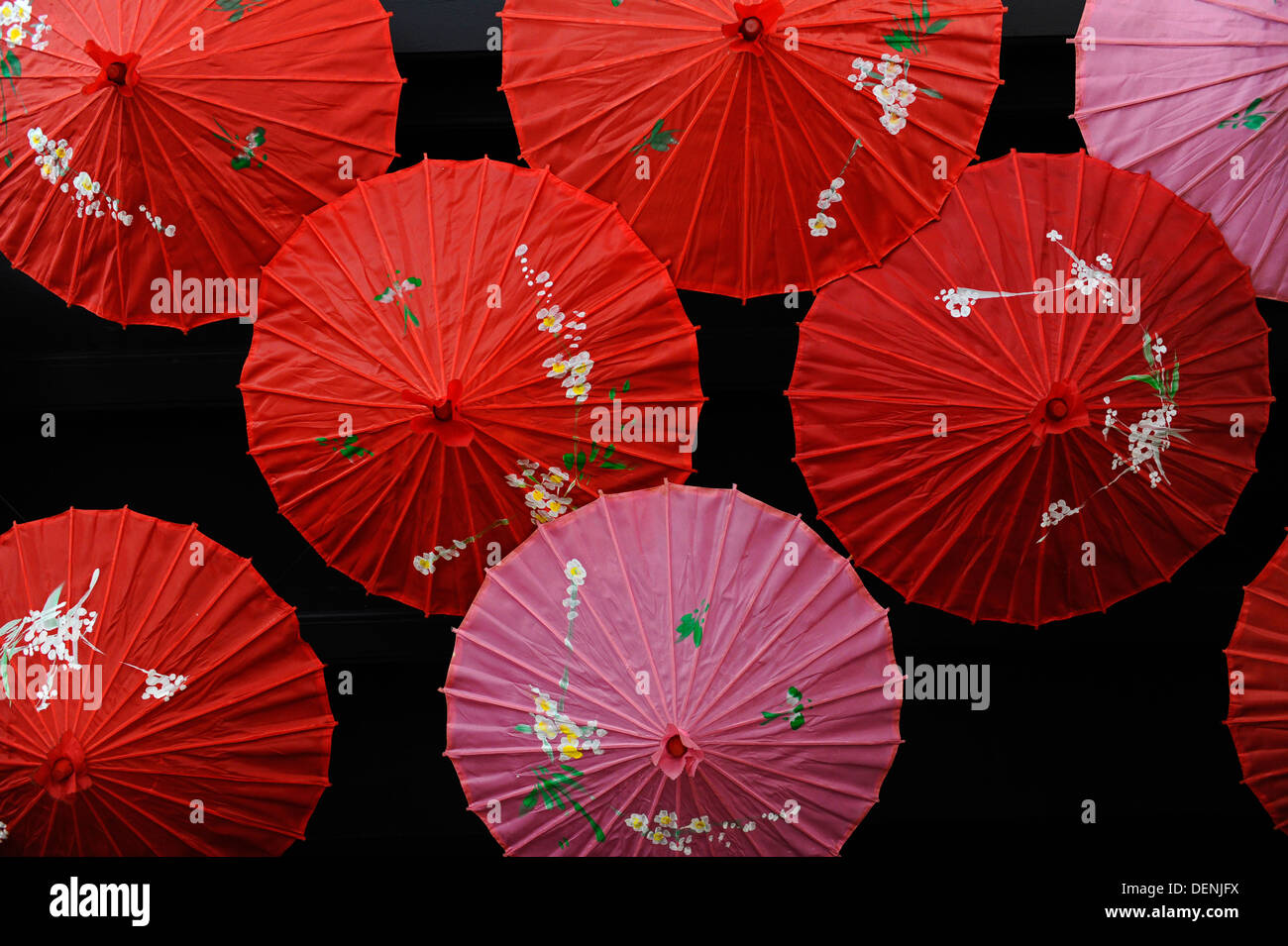 Rot und rosa Stil chinesische Sonnenschirme mit Blumenschmuck an der Decke eines Ladens. Stockfoto