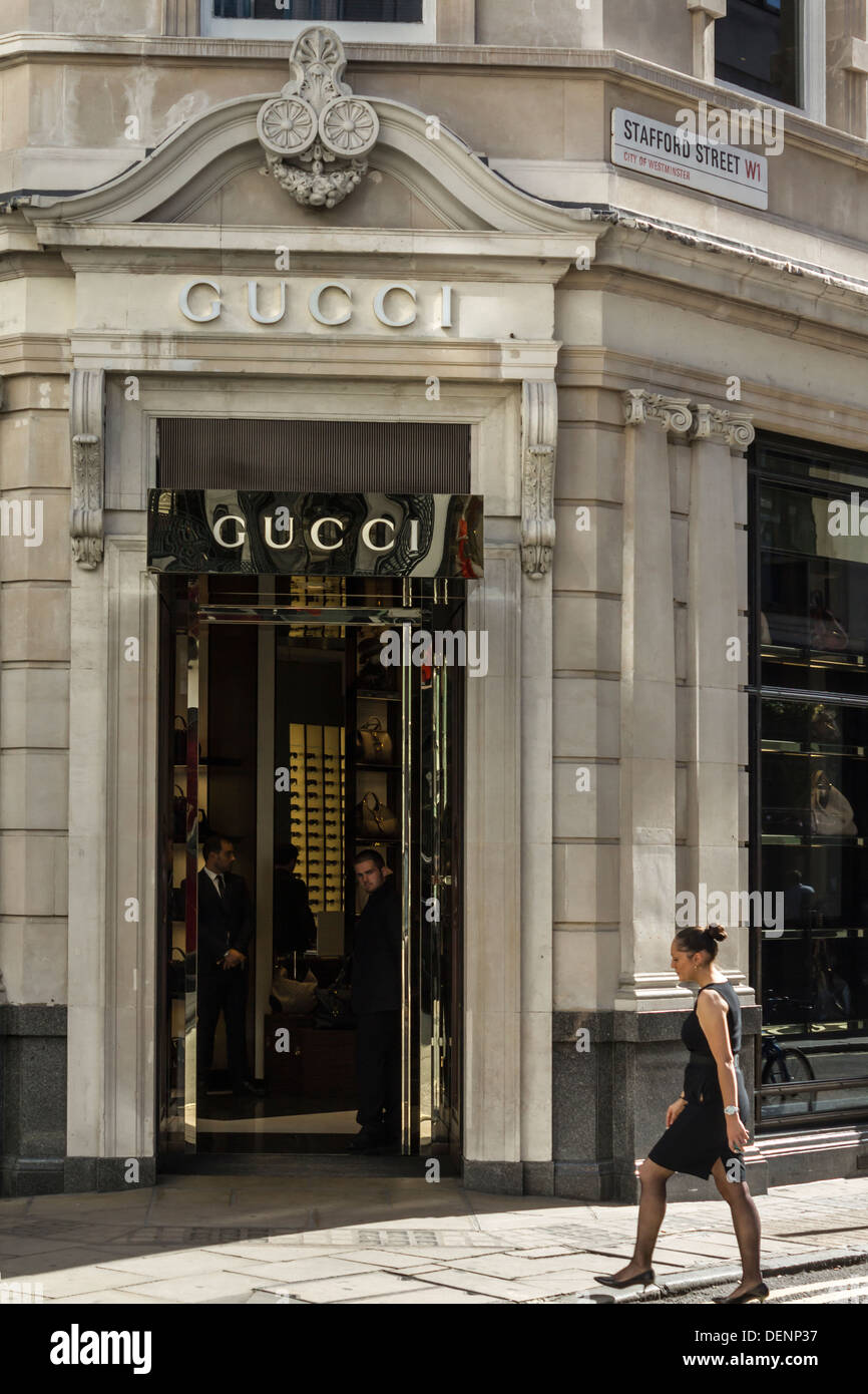 Frau geht von Mitarbeitern innerhalb der alten Bond St. Gucci Store Eingang London, UK Stockfoto