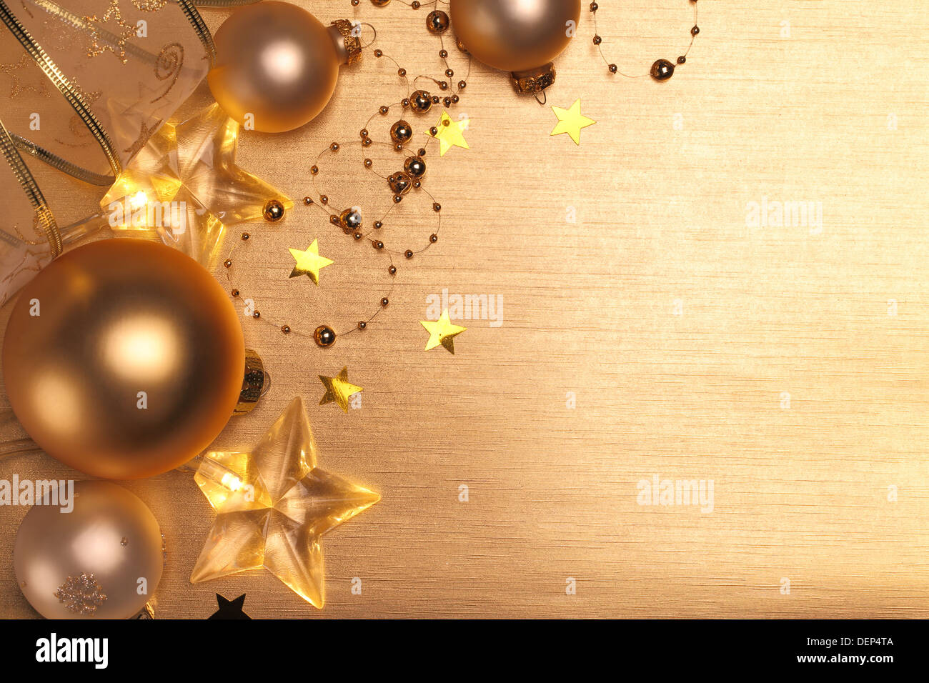 Weihnachtskugeln und Sterne leuchten auf goldenem Hintergrund Stockfoto