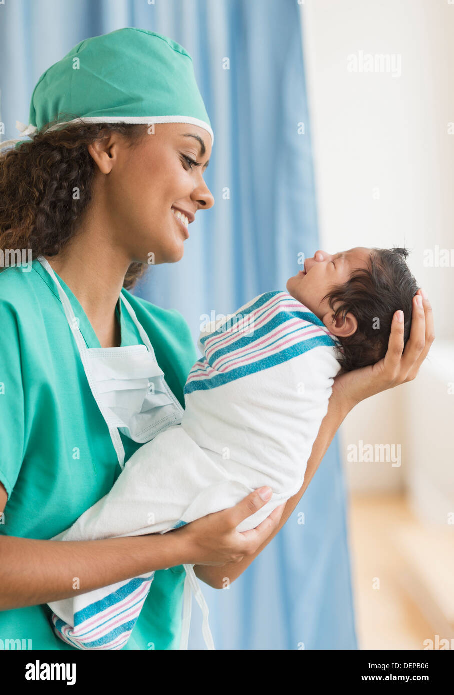 Hispanische Arzt hält Neugeborenen im Krankenhaus Stockfoto