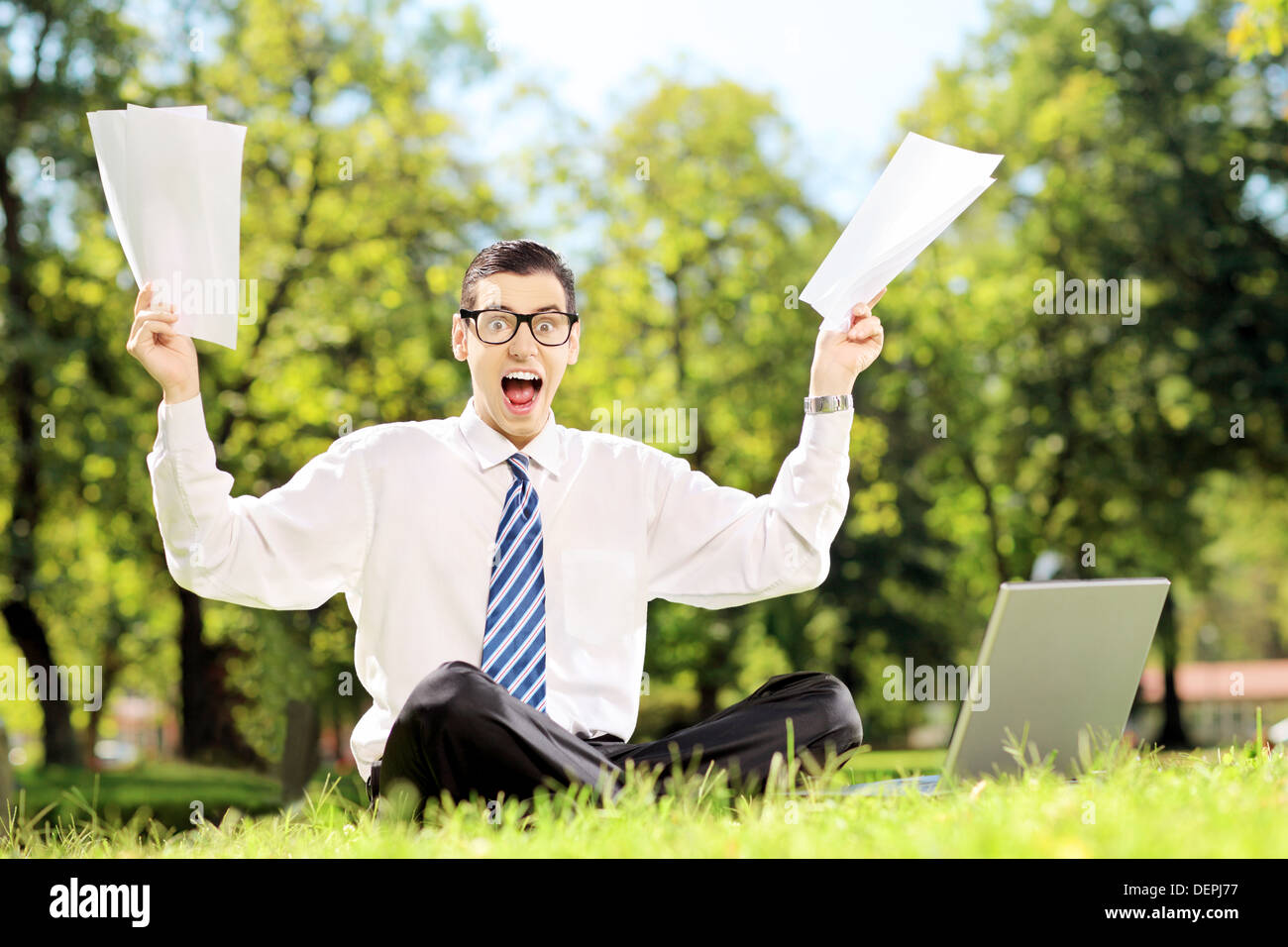 Besorgt Geschäftsmann Dokumente und schreien sitzen auf einer Wiese in einem park Stockfoto