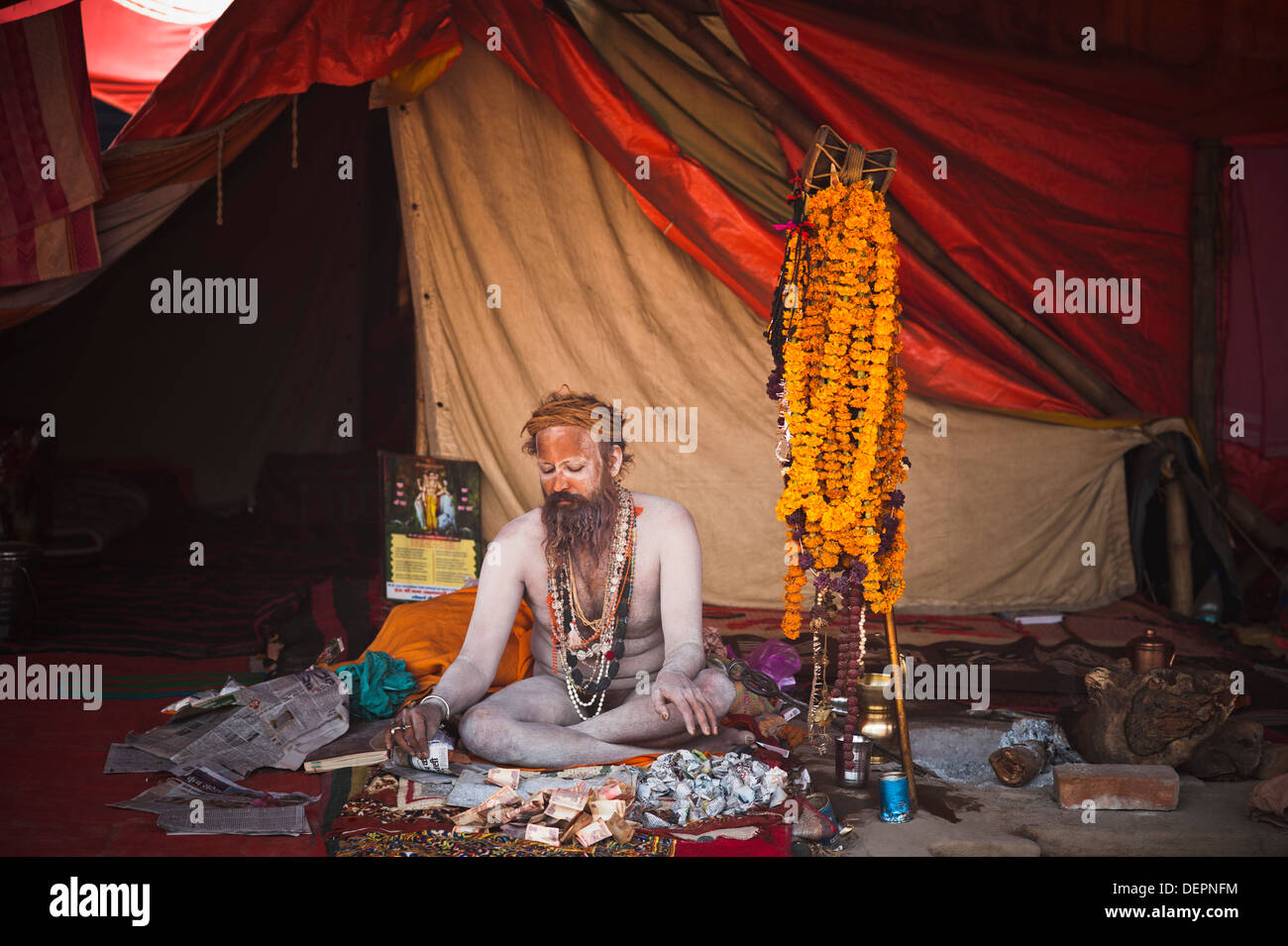 Naga Sadhu sitzen in einem Zelt mit dem Geld vor ihm Maha Kumbh, Allahabad, Uttar Pradesh, Indien Stockfoto