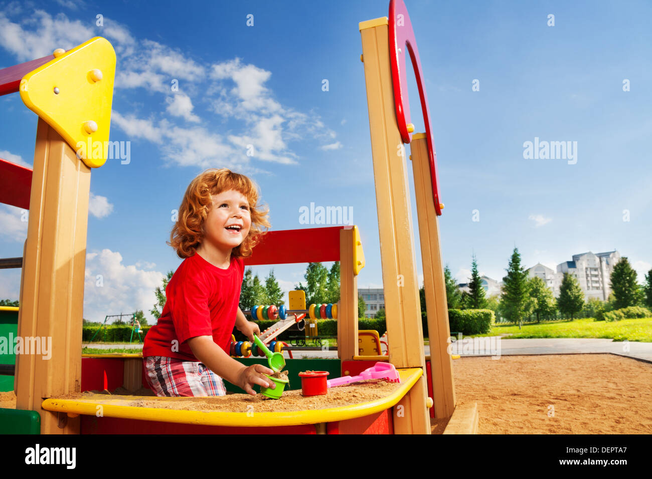 Glücklich lachende niedlichen kleinen drei Jahre alt Kind Jungen spielen im Sandkasten Stockfoto