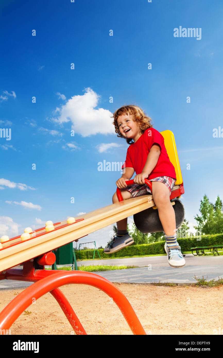 Glücklich Lauging kleine dreijährige Kind sitzt auf der Wippe Stockfoto