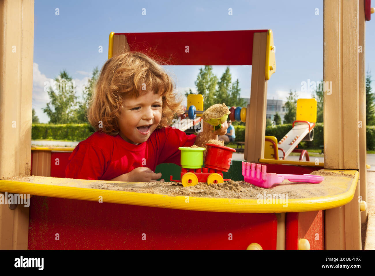 Kleiner Junge, drei Jahre alt spielt mit Sand auf Spielplatz Stockfoto