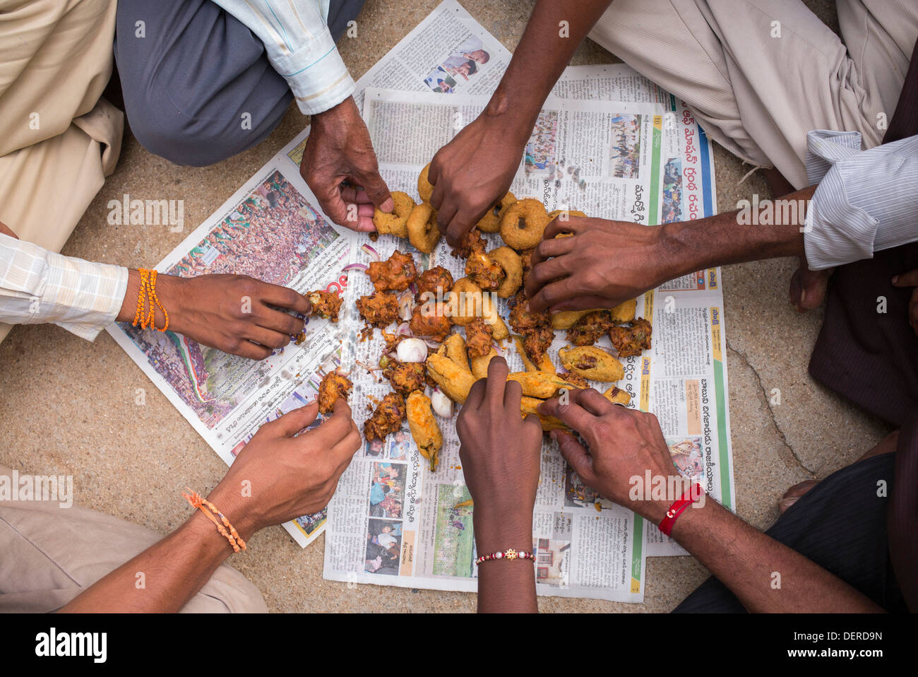 Indischen Mens richtigen Händen Kommissionierung auf ungesunde frittierte indischen Straße Speisen / fast Food. Andhra Pradesh, Indien Stockfoto