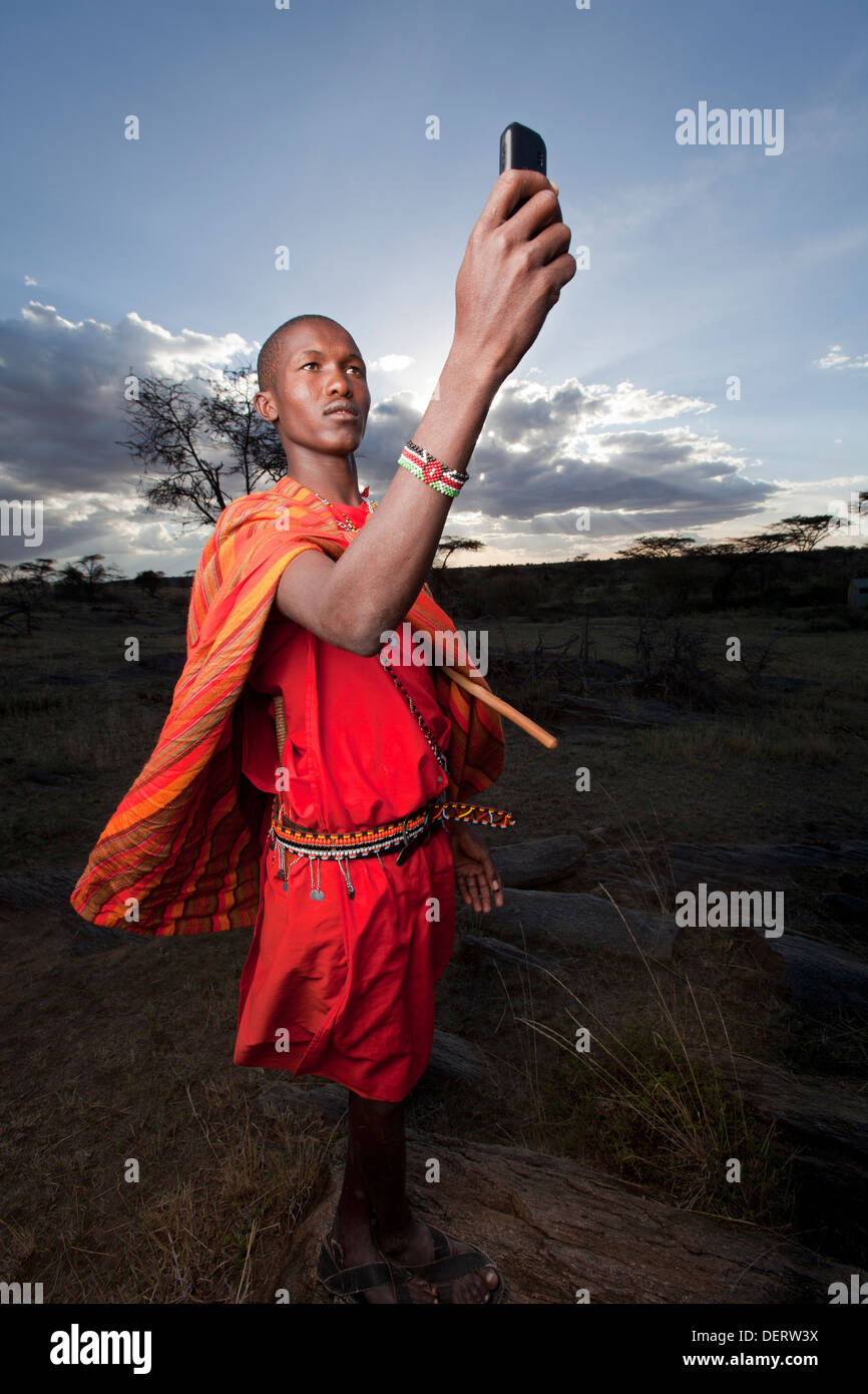 Maasai Handy hochhalten zu besseren Empfang, Mara-Region, Kenia. Stockfoto