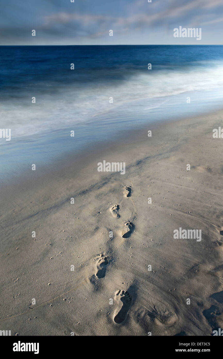 Fußspuren im Sand und verschwommen Meereswellen mit bewegte Wolken Stockfoto
