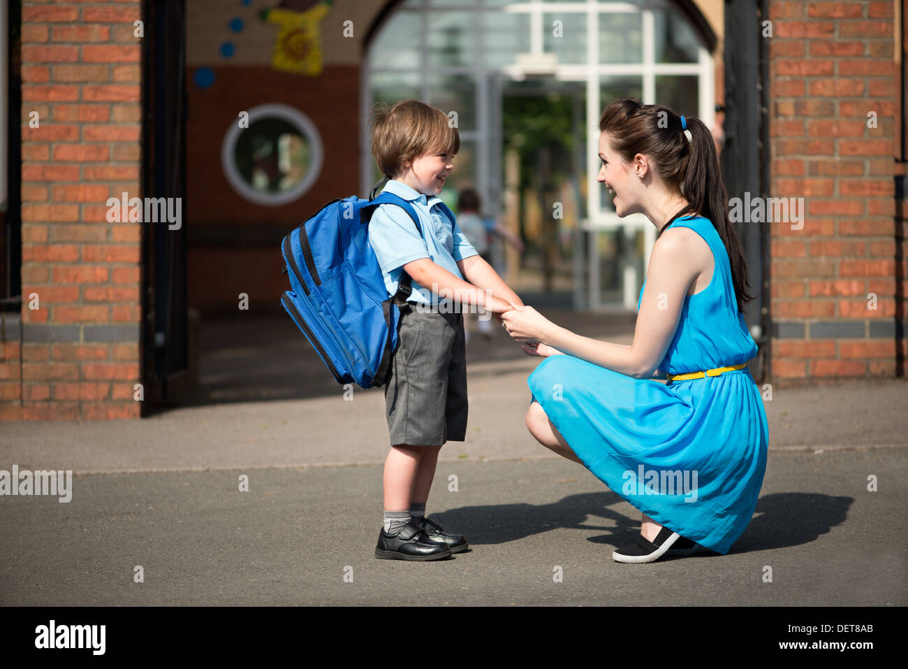 Eine attraktive glückliche junge Mama abholen oder Drop off ihr Sohn auf den Säugling Schule Tore Stockfoto