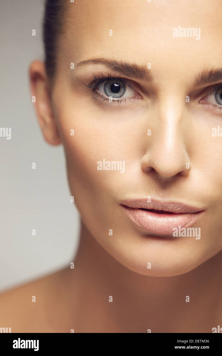 Close-up Portrait hübsche junge Frau mit perfekten gesunde Haut. Halbes Gesicht der schönen jungen Frau vor grauem Hintergrund Stockfoto