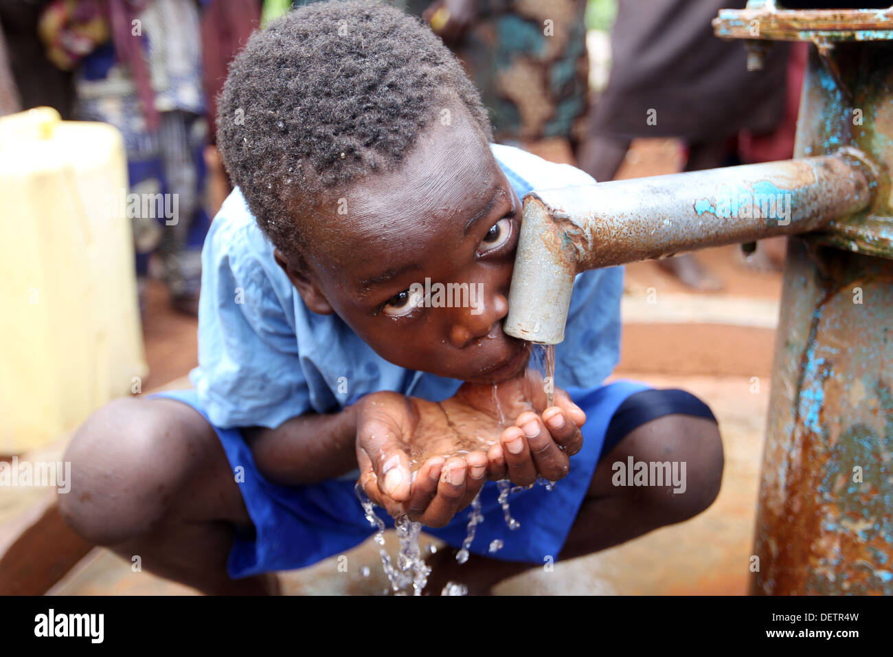 Ein kleiner Junge sammelt sauberes Wasser gepumpt, von einer NGO, die nun neben seinem Dorf im Bezirk Lira in Norduganda finanziert. Stockfoto