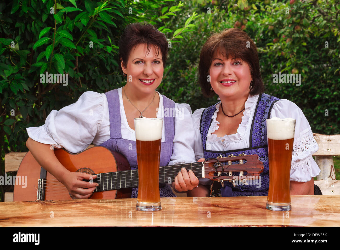 Ältere Frauen sitzen zusammen im bayerischen Dirndl und Musik in eine gemütliche halbe Weißbier Stockfoto