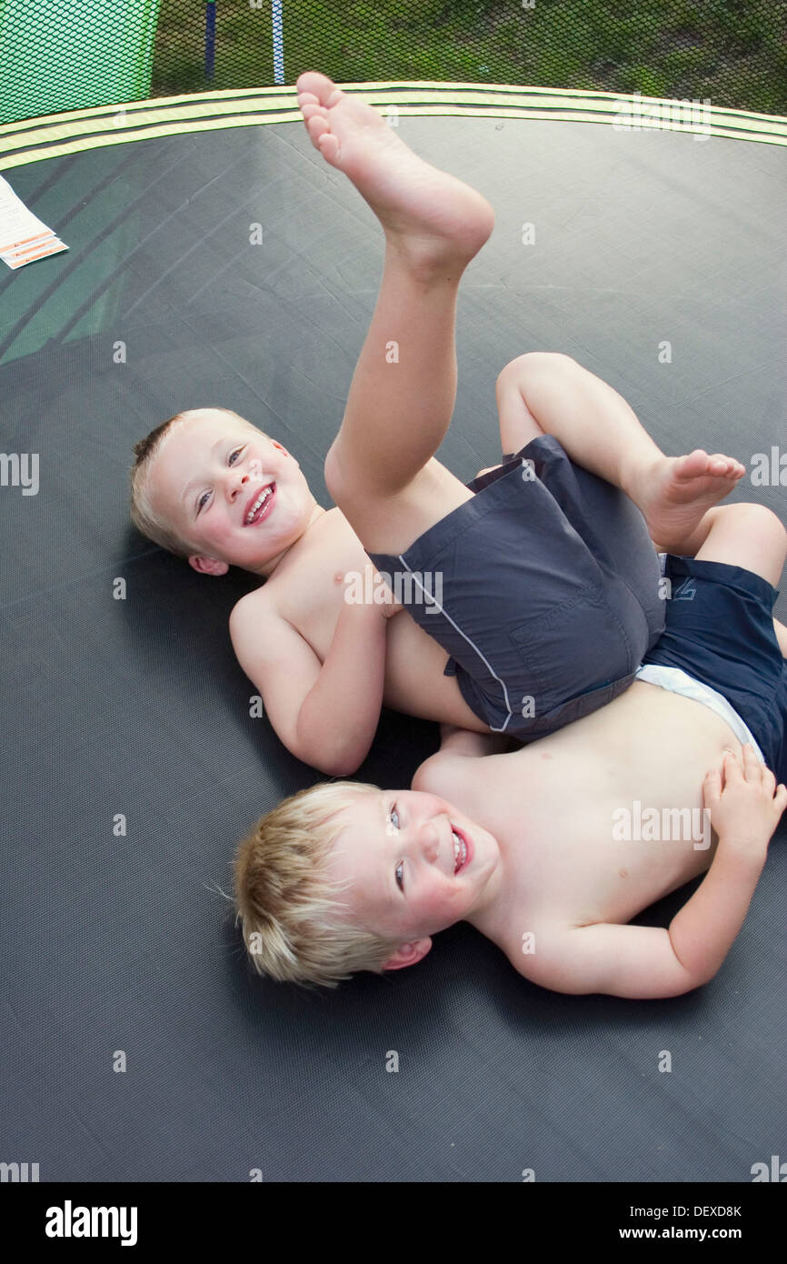 3 und 5 Jahre alten Jungen liegen auf dem Rücken auf einem Trampolin in  Kamera lachen Stockfotografie - Alamy