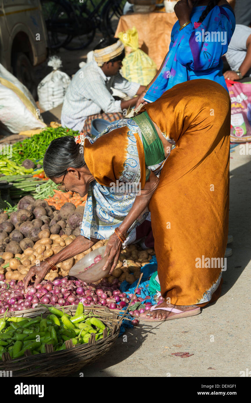 Indische Frau kaufen Zwiebeln aus einem Straßenmarkt in Puttaparthi, Andhra Pradesh, Indien Stockfoto