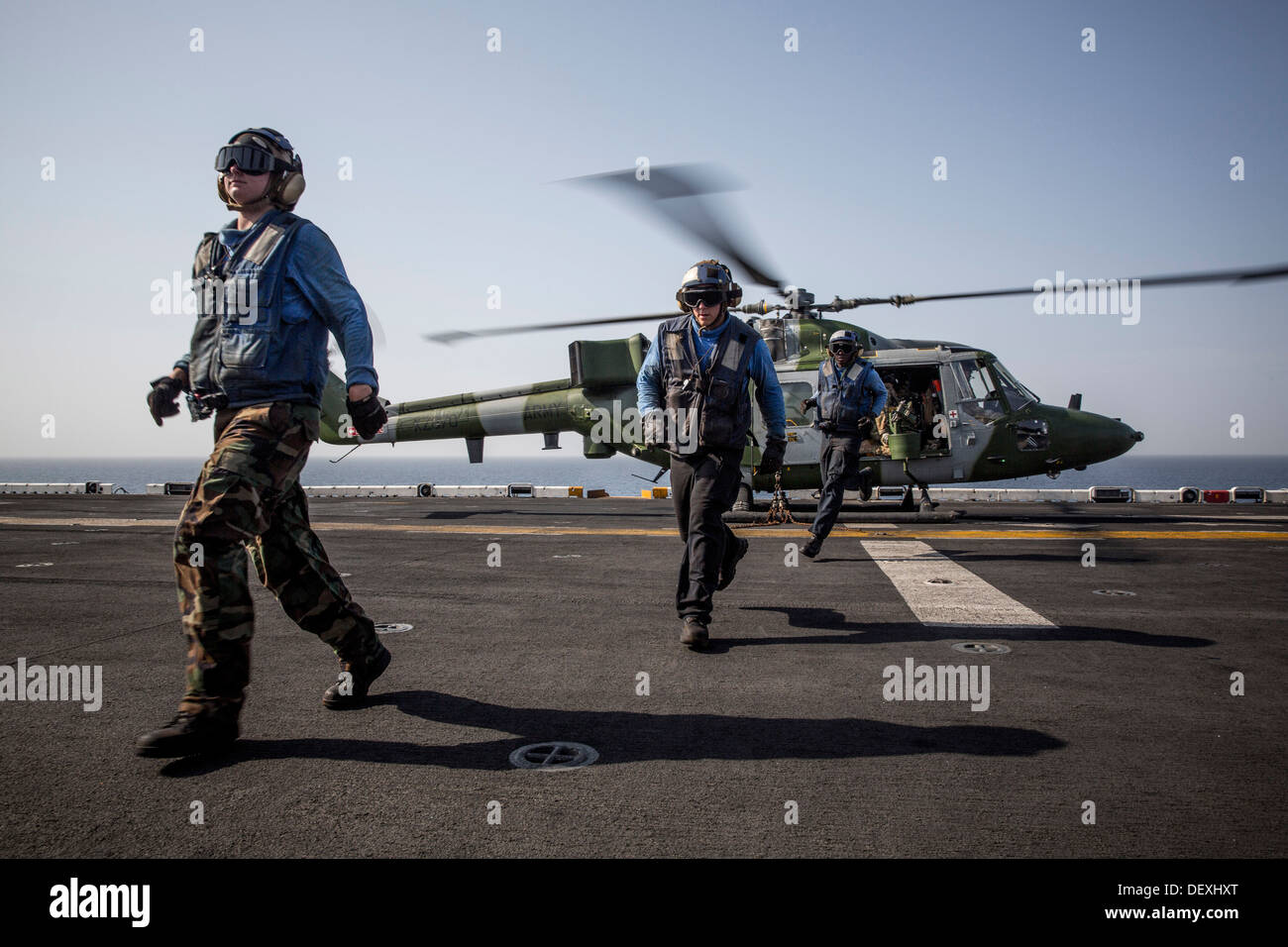 Matrosen laufen über die Foul-Linie nach Sicherung der British Royal Navy Lynx MK 8 Hubschrauber das Flugdeck der amphibischen Angriff Schiff USS Kearsarge (LHD-3). Kearsarge ist das Flaggschiff für die Kearsarge amphibische bereit Gruppe und mit der eingeschifften 26 Stockfoto